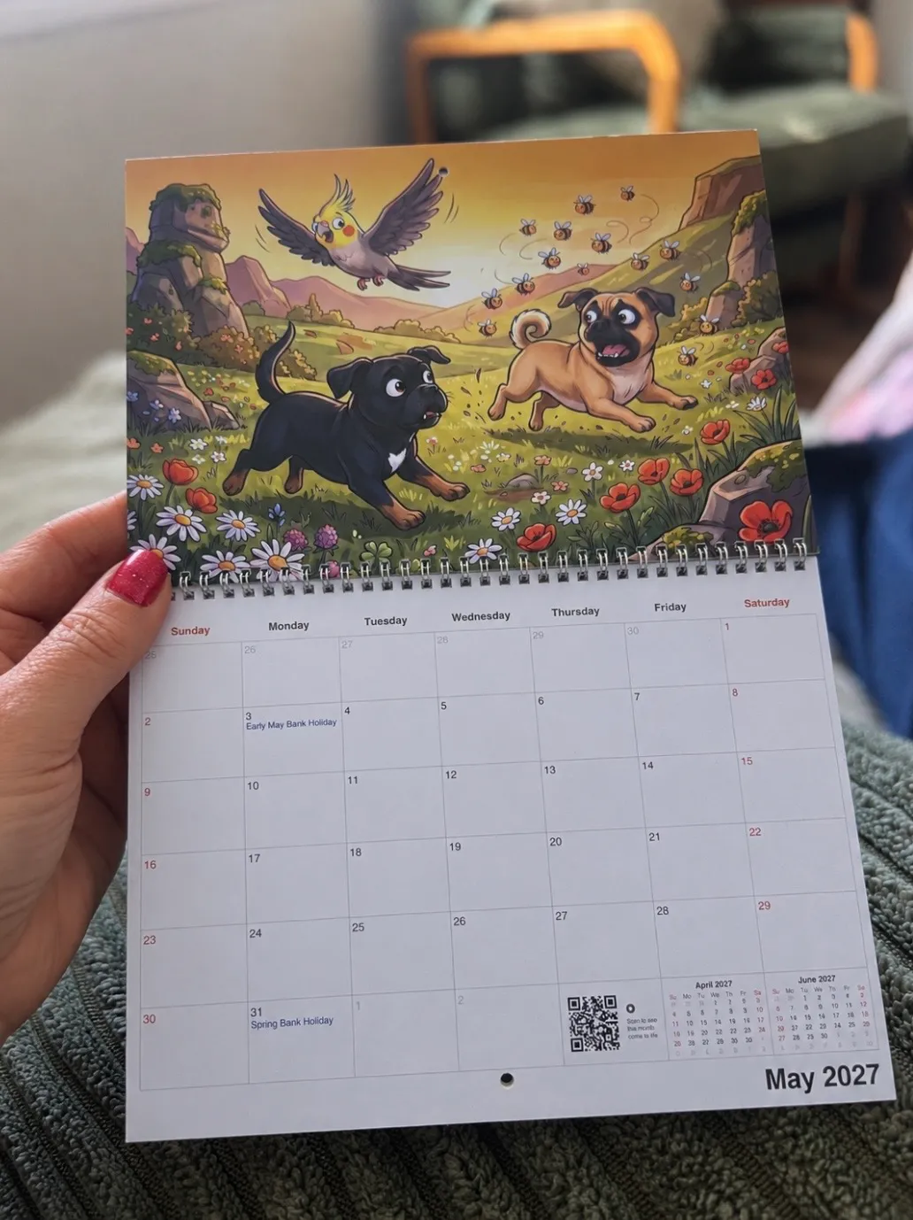 Someone’s hands holding a printed Funny Cartoon calendar showing two dogs and a bird running through a field.