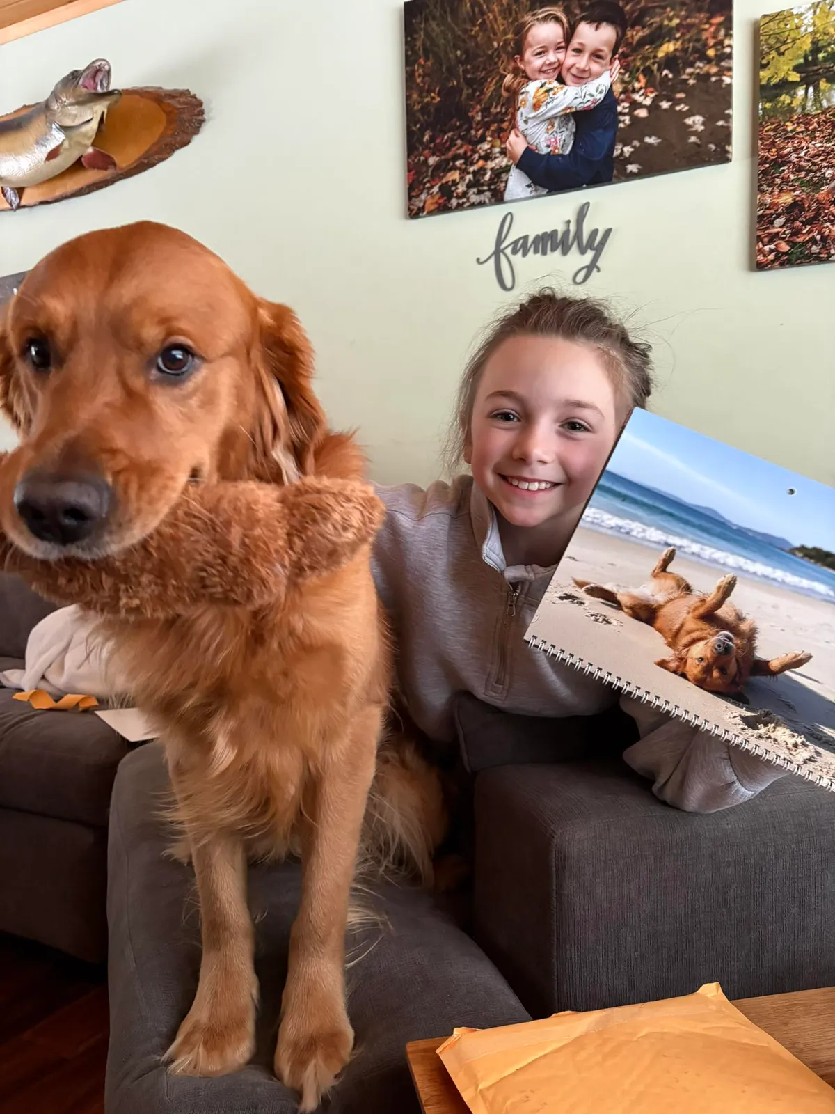 Un chien avec une peluche dans la bouche est assis à côté d’une personne tenant un calendrier Plein air imprimé.